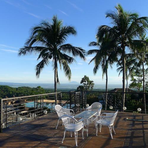 a table and chairs on a deck with palm trees at The Duyan House at Sinagtala Resort in Orani