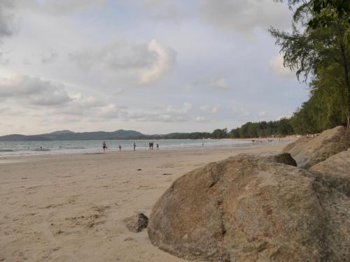 a beach with people in the water and a large rock at Marisa Garden Bungalow in Bang Tao Beach