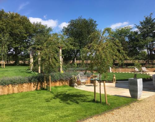 a garden with green grass and trees and a fence at Snipe Vineyard Cottage in Woodbridge