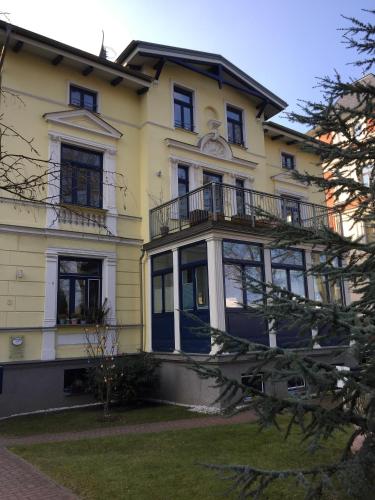 a large yellow house with balconies and a yard at Apartments in Warnemuende in Warnemünde