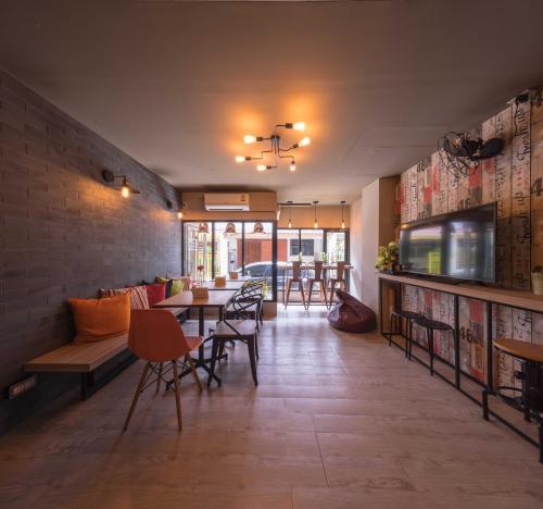 una sala da pranzo con tavoli e sedie e una TV di Augusta a Bangkok