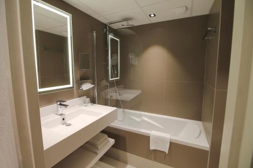 a bathroom with a sink and a tub and a mirror at Hotel Mercure Blois Centre in Blois