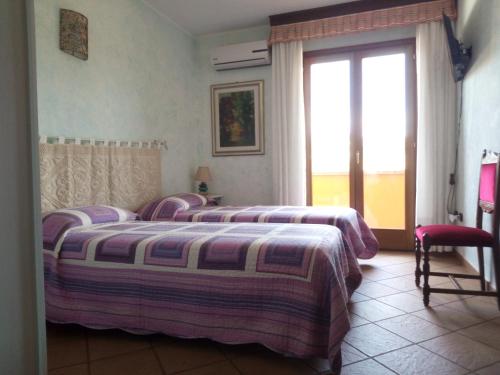 a bedroom with two beds and a large window at Grotta Delle Fate in Ossi