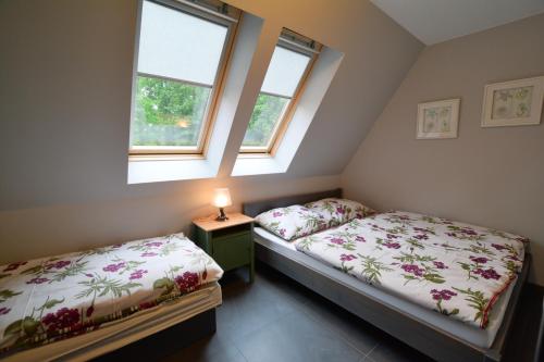 two beds in a room with two windows at Apartamenty PRIMA in Rewal