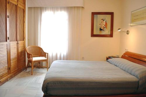 セビリアにあるDuplex Alamedaのベッドルーム1室(ベッド1台、椅子、窓付)