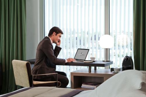 a man sitting at a desk in front of a laptop computer at Hôtel Barrière Lille in Lille