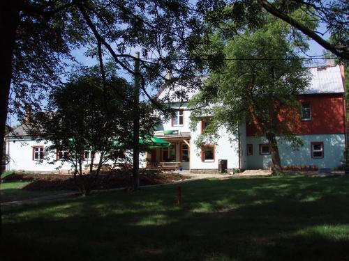 a large white house with trees in front of it at Penzion Slunečno in Dobšín