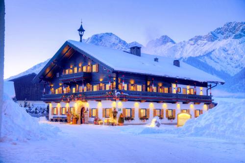 a large building in the snow with mountains at Thomanhof Chalet-Appartement in Saalfelden am Steinernen Meer