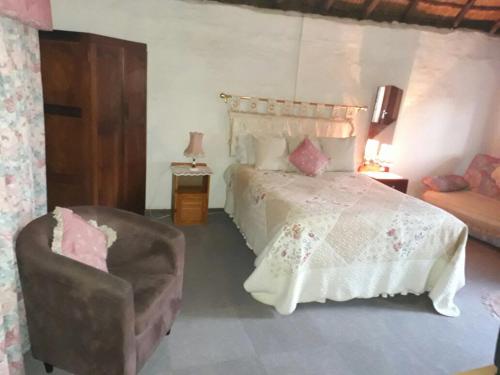 a bedroom with a large bed and a chair at Arbuckle House in Himeville