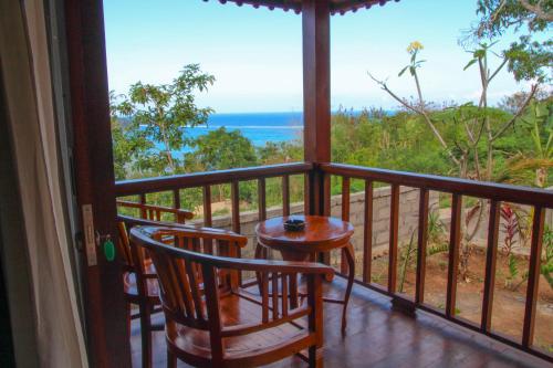 a balcony with two chairs and a table and a view of the ocean at Bukit Permata Lembongan in Nusa Lembongan