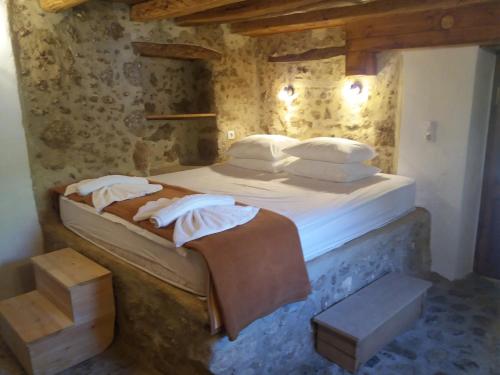 ein Schlafzimmer mit einem großen Bett mit weißer Bettwäsche und Kissen in der Unterkunft Heracles Traditional Cretan Houses in Spílion