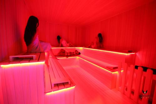 a woman sitting on a bench in a room with red lights at Vivaldi Park Hotel in Ankara