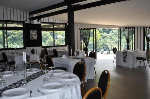 a dining room with white tables and chairs and windows at Le Relais de la Maroto in Pirae