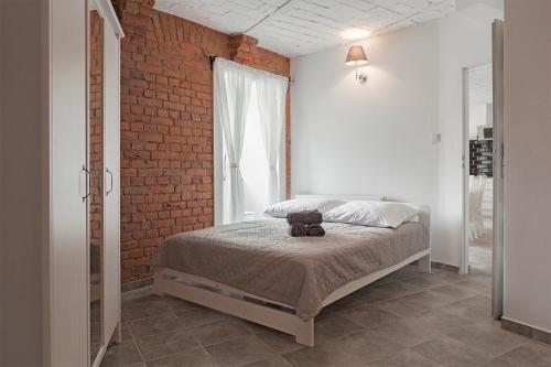 a bedroom with a bed and a brick wall at Apartament w starym browarze 2 in Kłodzko