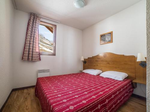 a bedroom with a red bed and a window at Noemys Chalets du Hameau des Aiguilles in Albiez-Montrond