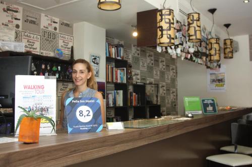a woman standing behind a counter in a store at Pella Inn Hostel in Athens