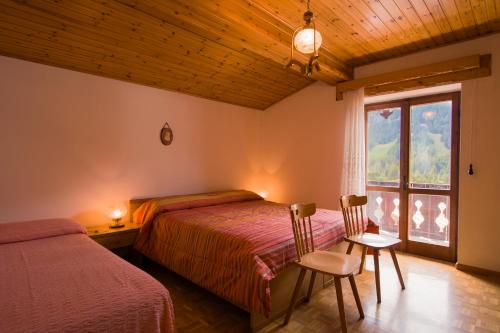 a bedroom with a bed and a window and two chairs at Appartamenti Anna Benedetti in Sappada