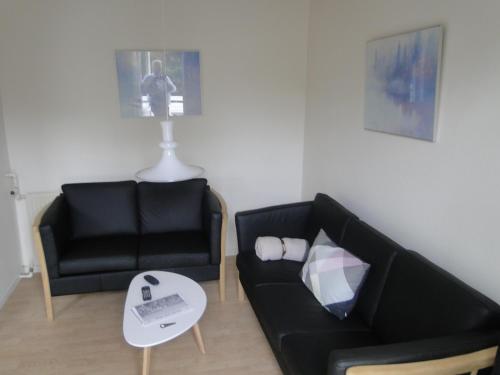 ein Wohnzimmer mit einem schwarzen Sofa und einem Tisch in der Unterkunft Thinghuskroen in Vestervig