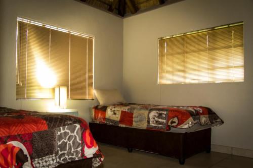 a bedroom with two beds and two windows at Impalas Walk in Marloth Park