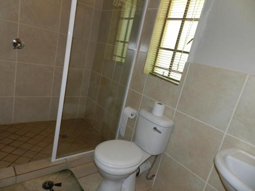 a bathroom with a toilet and a shower and a sink at Impalas Walk in Marloth Park