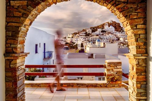 a person walking through an archway looking at a city at Ios Resort in Ios Chora
