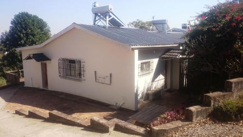 a white house with a gate and a fence at Sunset View Guest House in Piggs Peak