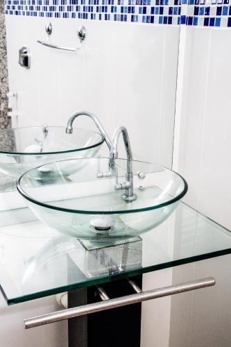 a bathroom with a glass sink on a glass counter at Pousada Das Araras in Itaúnas