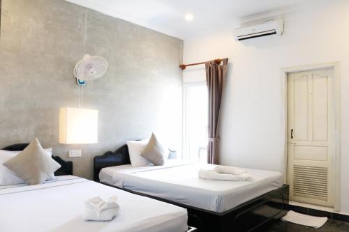 Habitación con 2 camas con sábanas blancas y ventana en Pool Party Hostel, en Siem Reap