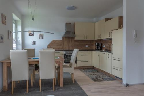 a kitchen with a wooden table and white chairs at Apartment Sofia in Bodensdorf