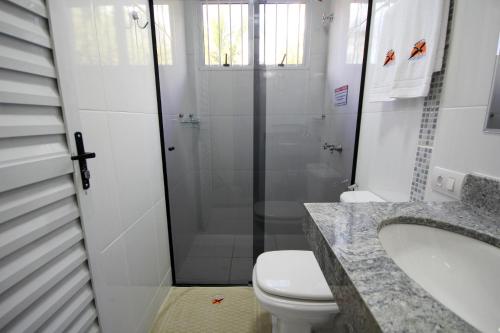 a bathroom with a shower and a toilet and a sink at Pousada Recanto Solar dos Pássaros in Olímpia