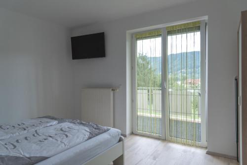 a bedroom with a bed and a sliding glass door at Apartment Sofia in Bodensdorf