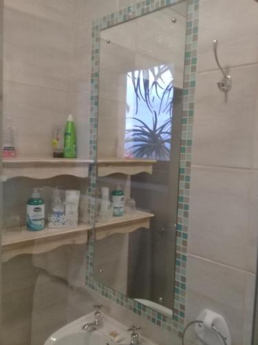 a bathroom with a mirror and a sink at A1 Kynaston Guest House bed and breakfast or self catering in Jeffreys Bay