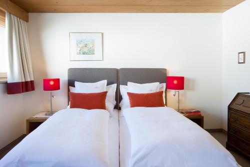 two beds in a bedroom with two red lamps at Hotel Angela in Lech am Arlberg