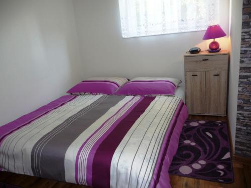 ヤストシェンビャ・グラにあるDomek Miłkaのベッドルーム1室(紫のシーツとランプ付きのベッド1台付)