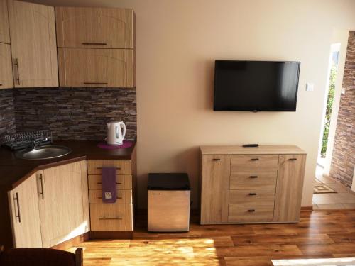 a kitchen with wooden cabinets and a flat screen tv on the wall at Domek Miłka in Jastrzębia Góra