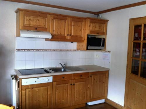une cuisine avec des armoires en bois et un évier dans l'établissement Studio d'Anaite, aux Houches