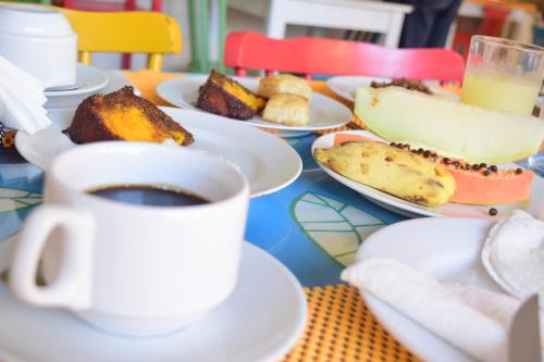 a table with plates of food and a cup of coffee at Paranambuca Pousada in Porto De Galinhas