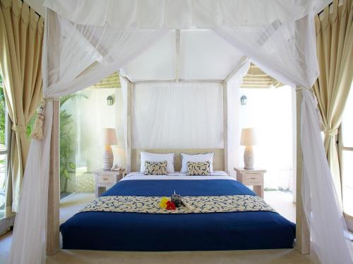 a bedroom with a blue bed with a canopy at Artemis Villa Hotel in Seminyak