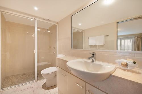 a bathroom with a sink and a toilet and a mirror at Riverside Holiday Apartments in Ballina