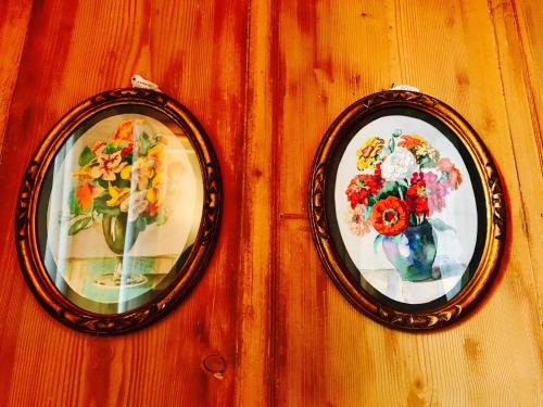 two pictures of flowers in vases on a wall at Auberge de l'Assesseur - Mont-Soleil in Saint-Imier