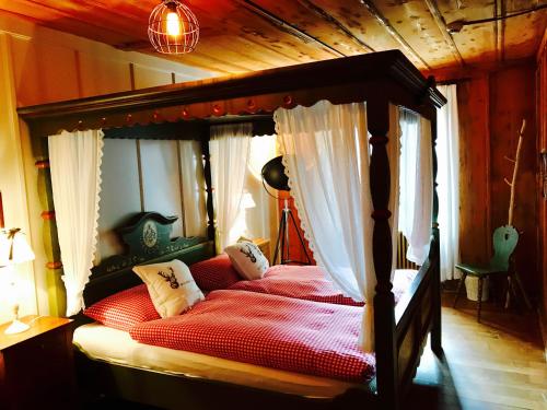 a bedroom with a canopy bed with red sheets at Auberge de l'Assesseur - Mont-Soleil in Saint-Imier