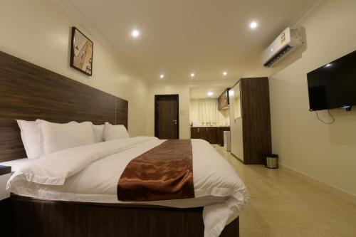 a bedroom with a large bed and a flat screen tv at Top View Apartments in Al Hofuf