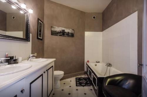 a bathroom with a sink and a toilet and a tub at Maison de charme 1930 proche Lyon in Lentilly