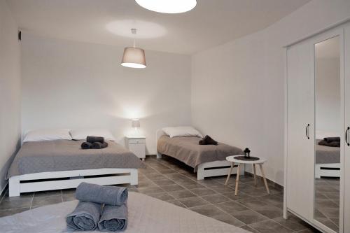 a white bedroom with two beds and a table at Apartamenty w Starym Browarze 3 in Kłodzko