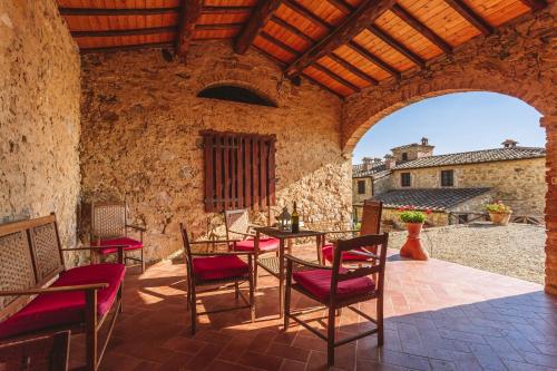 an outdoor patio with chairs and tables and a stone wall at Ormanni nel Chianti Classico in Barberino di Val dʼElsa