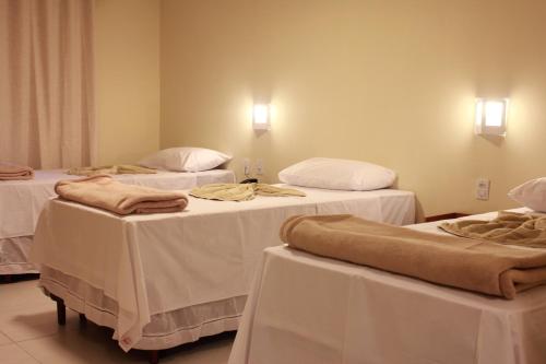 a room with three beds with white tables at Costa Dourada Pousada in Arraial do Cabo