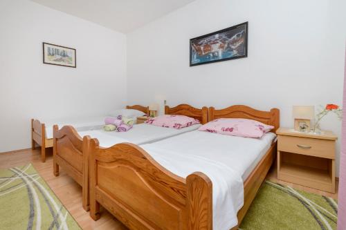 a bedroom with a wooden bed with pink pillows at Oreb Dream Apartments in Koločep