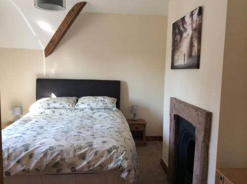 a bedroom with a bed and a fireplace at St Matthews cottages in Allonby