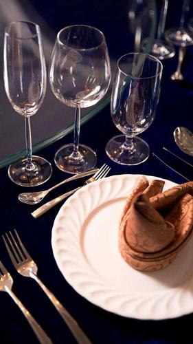 a table with a plate of food and wine glasses at Pensiunea Dely_Cios in Vălenii de Munte
