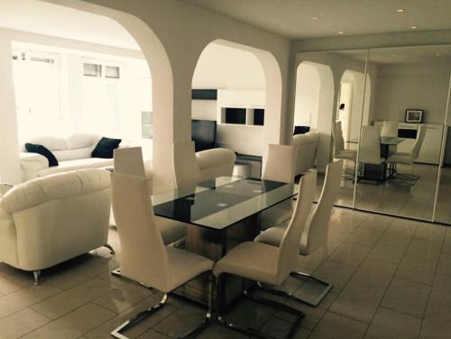 a living room with a glass table and white chairs at Ferienwohnung Amperblick Fürstenfeldbruck in Fürstenfeldbruck
